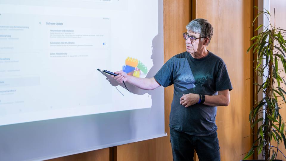 Ein Referent erläutert anhand einer projizierten Computeroberfläche die Durchführung eines Software-Updates.